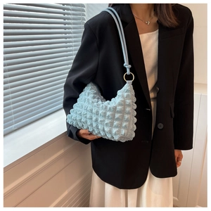 Detail of light blue bubble textured fabric bag with gold metal ring accents and strap