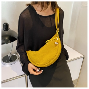Detail of a bright yellow nylon crescent crossbody bag with a cute duck charm on model