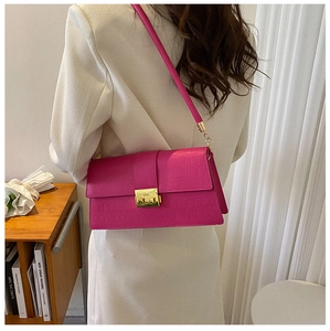 Detail of magenta crocodile embossed leather shoulder bag with a gold rectangular metal lock
