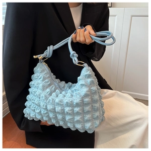 Detail of light blue bubble textured pleated shoulder bag with golden hardware