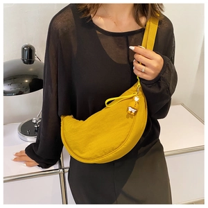 Detail of bright yellow nylon crescent bag with a cute duck charm on a model