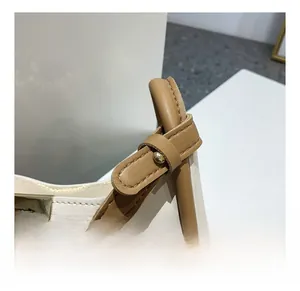 Gros plan sur la bandoulière en cuir marron avec boucle métallique dorée et coutures