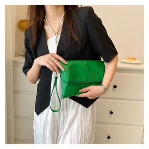 Primer plano de bolso sobre plegable verde brillante con correa de mano para mujer
