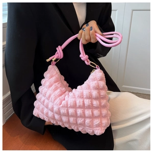 Macro view of pink bubble textured shoulder bag with knotted strap and gold hardware