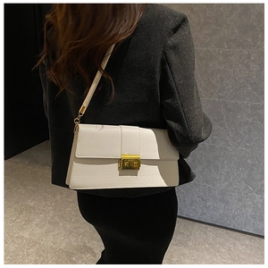 Close-up of white croc-embossed shoulder bag featuring a gold square metallic lock