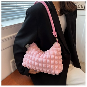 Detail of pink waffle texture underarm bag with decorative knot and gold hardware