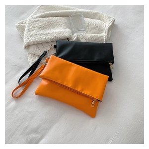 Detalle de bolsos sobre de cuero en negro y naranja con cremalleras doradas y correas