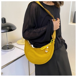 Detail view of yellow nylon crescent crossbody bag with adjustable strap and cute duck charm