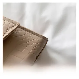Close-up of beige faux crocodile leather texture and precision stitching on a shoulder bag