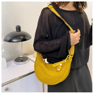 Detail of bright yellow nylon crescent crossbody bag with cute duck charm on model