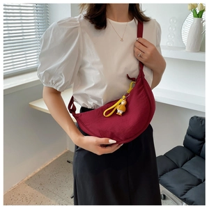 Detail of burgundy half-moon nylon crossbody bag with a cute yellow duck pendant