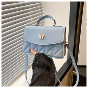 Detail of light blue square bag featuring geometric embossing and gold butterfly clasp