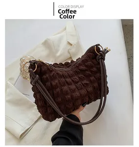 Detail of coffee bubble textured fabric underarm bag with thin brown leather straps