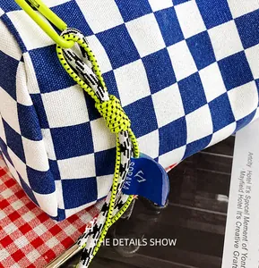 Detail der blau karierten Baguette-Tasche mit neongrüner Kordel und Marken-Webetikett