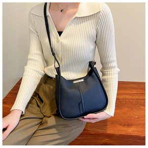Vue lifestyle d'un sac seau noir en cuir litchi porté par un mannequin sur des escaliers