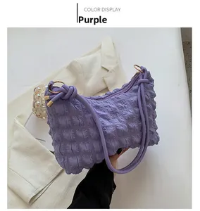 Detail of purple bubble textured shoulder bag with knotted strap and metallic ring buckle