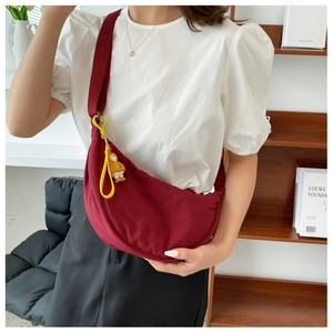 Detail of burgundy half-moon nylon crossbody bag with a cute yellow duck charm