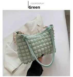 Detail of mint green popcorn texture fabric and gold hardware on a stylish shoulder bag