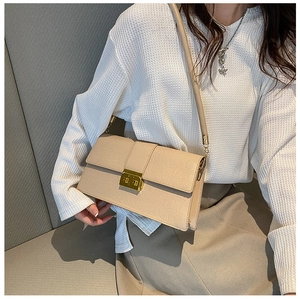 Chic beige crocodile embossed square handbag styled on shoulder with minimalist outfit