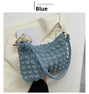 Close-up of blue bubble textured hobo bag with zip closure on stylish blazer