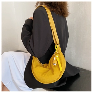 Close-up of vibrant yellow nylon half-moon crossbody bag with a cute charm pendant