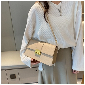 Detail of beige faux crocodile skin texture and gold square lock on stylish flap bag