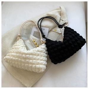Close-up of stylish popcorn texture shoulder bags in cream and black fabric