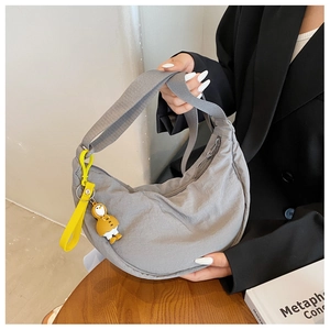 Grey nylon half-moon crossbody bag detail with a cute yellow penguin charm accessory