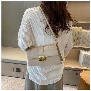 Close-up of beige crocodile pattern shoulder bag with golden buckle and sleek leather strap