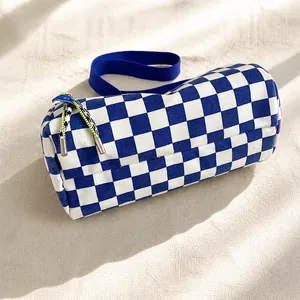 Detail der blau karierten Zylindertasche mit Stoffriemen auf einem Schreibtisch