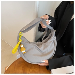 Detail of grey nylon crescent bag featuring a wide strap and yellow duck charm