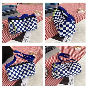 Detailansicht der karierten Zylindertasche mit blauem Gurt und neongrünem Reißverschluss