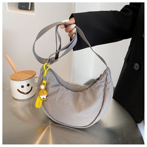 Grey nylon half-moon crossbody bag with a yellow duck pendant shown on a model