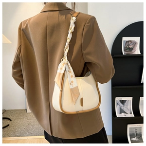 Détail du sac seau beige avec foulard en soie décoratif sur la bandoulière du sac