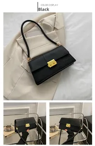 Detailed view of crocodile embossed leather texture and gold metal clasp on black handbag