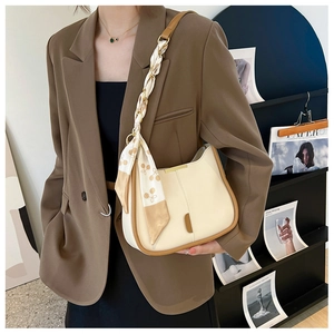 Détail d'un sac crème élégant avec bandoulière en chaîne enroulée d'un foulard en soie