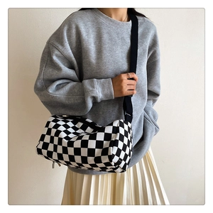Détail du sac cylindrique à damier avec bandoulière réglable porté par un mannequin