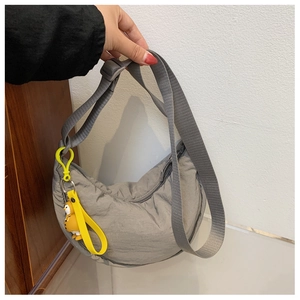 Detailed shot of a grey nylon crescent crossbody bag featuring a bright yellow charm