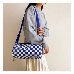 Détail du sac polochon à damier avec bandoulière bleue et accents néon au zip