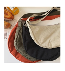 Stack of nylon crescent crossbody bags in various colors for casual picnic style