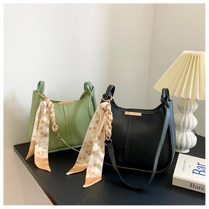 Détail de sacs seaux en cuir minimalistes vert et noir avec anses foulard en soie
