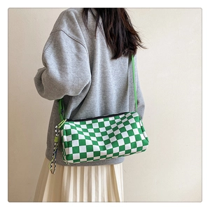Détail du sac cylindre à damier vert porté sur une tenue décontractée moderne