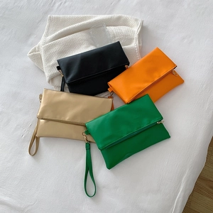 Carteras de sobre plegables en negro, naranja, dorado y verde con correas de mano
