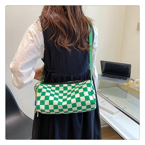 Detail einer grünen Schachbrett-Zylindertasche mit verstellbarem Riemen am Modell