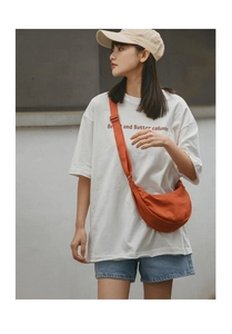 Outdoor shot of bright orange half-moon crossbody bag in soft nylon with adjustable strap