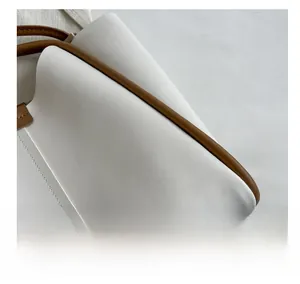 Close-up of white leather tote with brown piping showing refined stitching and texture