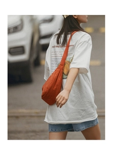 Detail of a caramel nylon crescent bag paired with a graphic oversized white t-shirt