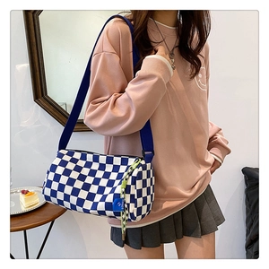 Detail der blau-weißen Schachbrett-Zylindertasche mit Riemen in lässigem Lifestyle-Ambiente