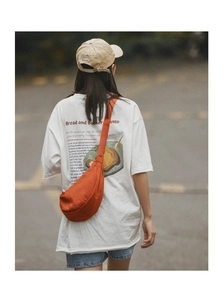 Outdoor street view of a vibrant orange nylon crossbody dumpling bag with wide strap