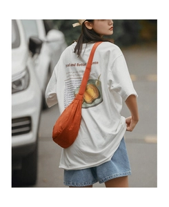 Detailed view of an orange crossbody bag paired with a white graphic t-shirt and denim shorts